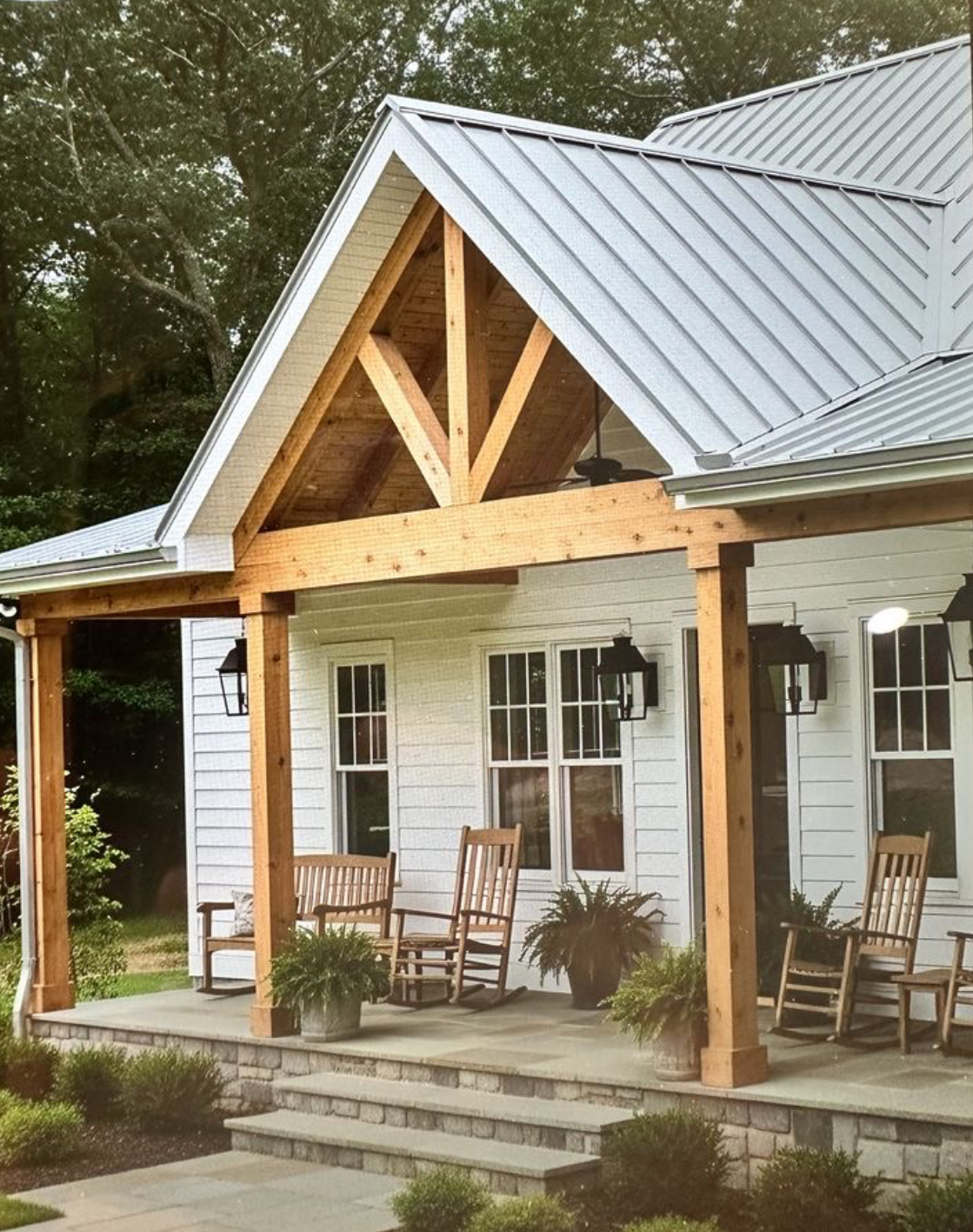 Custom timber-frame front porch with standing seam metal roof on a white farmhouse